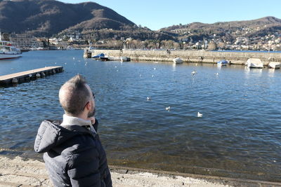 Rear view of man standing by lake against mountain
