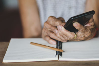 Midsection of woman holding paper with text on table
