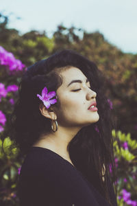 Woman with flower on head standing against tree at park