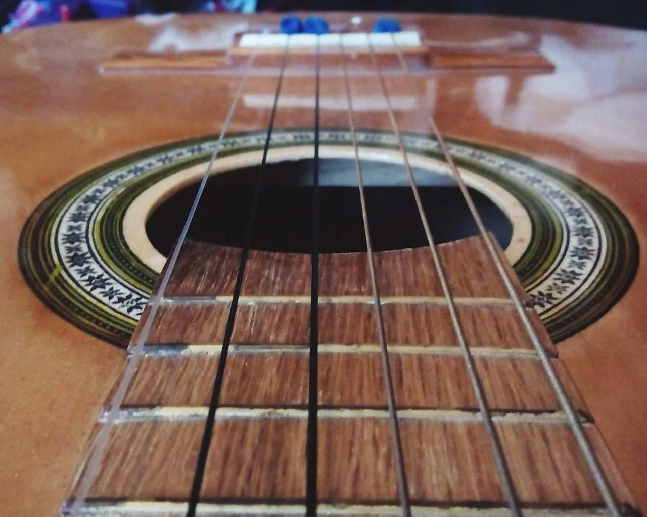 music, indoors, musical instrument, arts culture and entertainment, musical equipment, musical instrument string, guitar, close-up, wood - material, part of, selective focus, technology, focus on foreground, no people, acoustic guitar, metal, high angle view, low angle view, modern, cropped