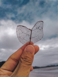 Close-up of hand holding heart shape against sky