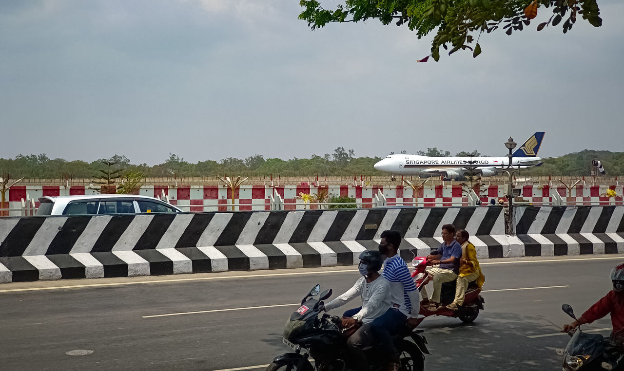 transportation, group of people, race track, mode of transportation, vehicle, crowd, large group of people, in a row, sports, race, sport venue, men, person, road, racing, motorcycle, adult, nature, day, land vehicle, sky, outdoors, sports race, motorcycling