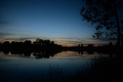 Silhouette trees by lake against sky during sunset