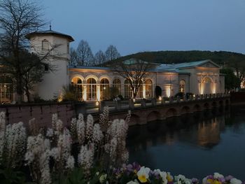 Arch bridge over river by buildings against sky