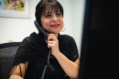 Smiling woman talking on telephone in office