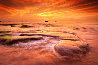 Scenic view of sea against dramatic sky during sunset