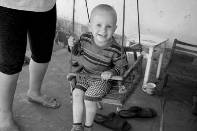 Portrait of boy smiling while sitting on swing