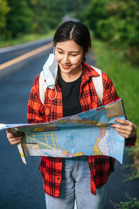 Young woman holding umbrella while standing outdoors