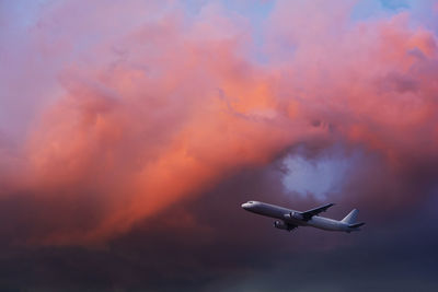 Low angle view of airplane flying against sky during sunset