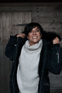 Portrait of smiling woman wearing winter coat at home