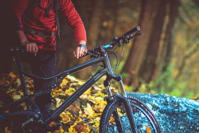 Midsection of man with bicycle in forest