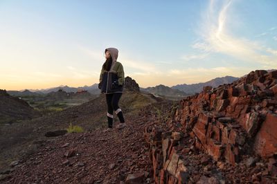 Man standing on rock against sky during sunset