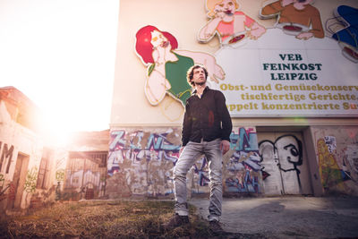 Full length of man standing against graffiti wall