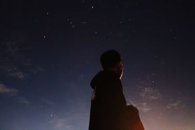 Low angle view of silhouette man standing against sky at night