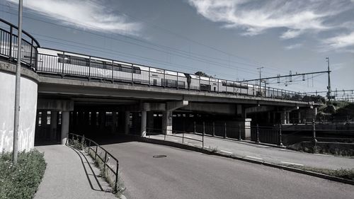 Train on bridge over road against sky