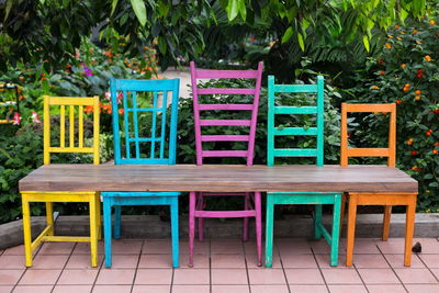 Bench made of five recycled wood chairs in different sizes and colours and wood plank