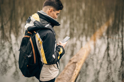 Side view of young man using mobile phone in winter