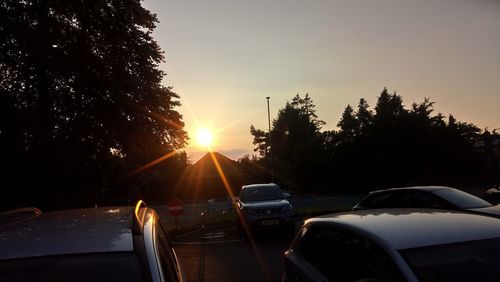 Cars on road against sky during sunset