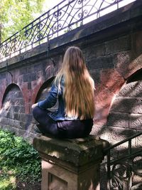 Rear view of woman sitting on bridge