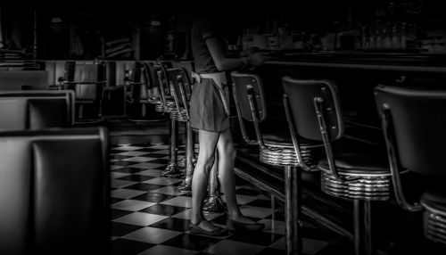 Rear view of woman standing on chairs