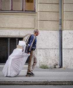 Man holding umbrella while standing against built structure