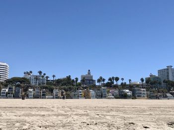 Buildings by beach against clear blue sky