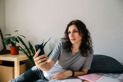 A young brunette woman is resting at home and talking on a smartphone