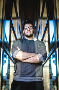 Portrait of young man standing by window