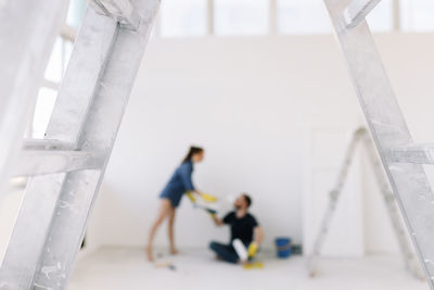 A young couple in love have moved into a new house and are making repairs painting white walls