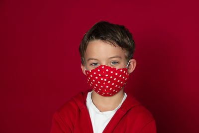 Close-up portrait of boy against red background