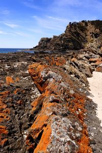 Rock formation on beach against sky