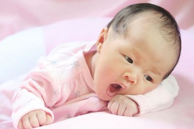 Portrait of cute baby lying on bed