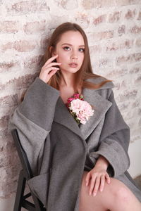 Fashion model wearing warm woolen gray coat decorated with pink  roses, spring floral theme