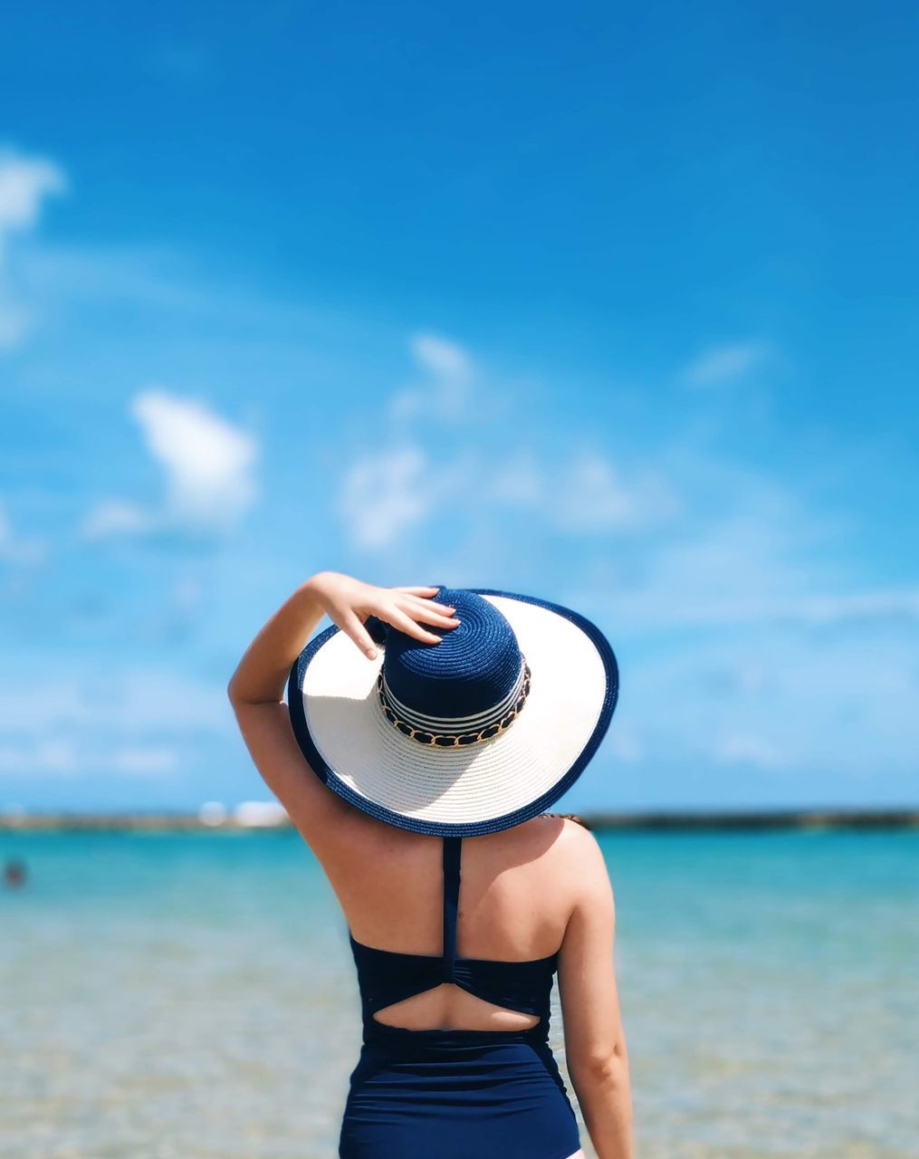 hat, one person, sea, clothing, sky, water, leisure activity, lifestyles, women, real people, vacations, beach, trip, holiday, day, adult, land, horizon, nature, horizon over water, outdoors, sun hat, turquoise colored