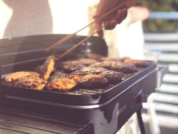 Cropped hand of person preparing meat on barbecue grill