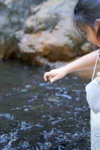 Midsection of woman on rock in water