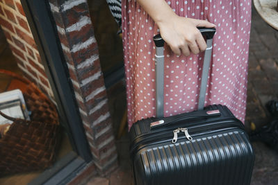Midsection of woman holding suitcase