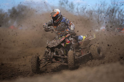 Racer riding quadbike in dirt during race