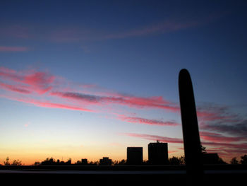 Silhouette factory against sky during sunset