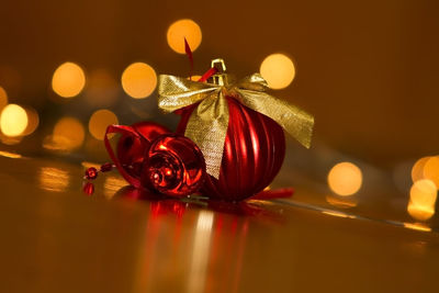 Close-up of christmas bauble against illuminated lights on table