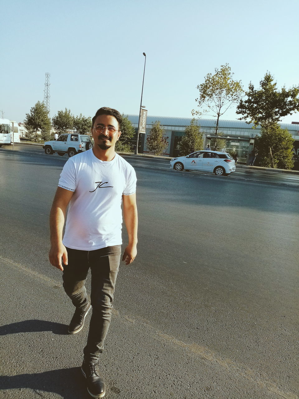 FULL LENGTH PORTRAIT OF YOUNG MAN STANDING ON ROAD AGAINST CLEAR SKY