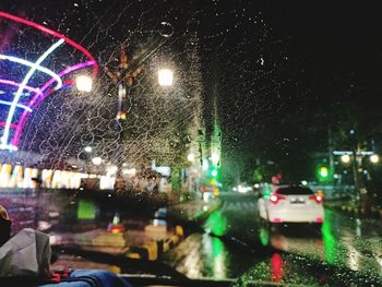 Cars on illuminated street during rainy season at night