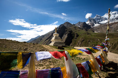 Multi colored flags hanging on mountain against sky