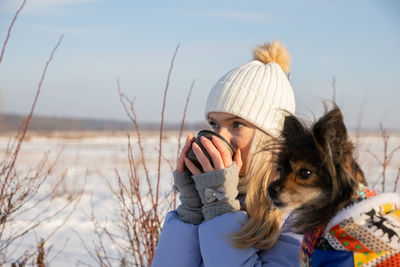 Rear view of woman with dog on field against sky