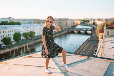 Full length of woman standing on mobile phone in city