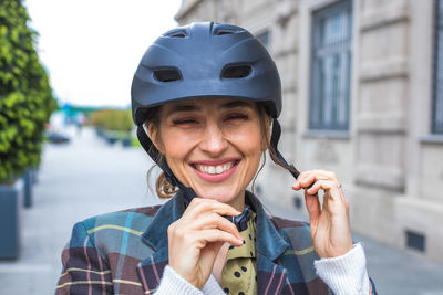 Portrait of young woman putting bicycle protective helmet