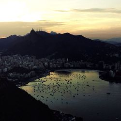 Scenic view of river and mountains against sky at sunset