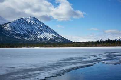 Scenic view of frozen lake by snowcapped mountains against sky