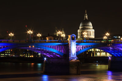 Illuminated bridge over river at night