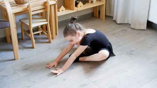 High angle view of girl sitting on hardwood floor at home